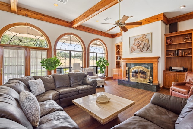 living room featuring built in features, a premium fireplace, dark wood-type flooring, ceiling fan, and beam ceiling