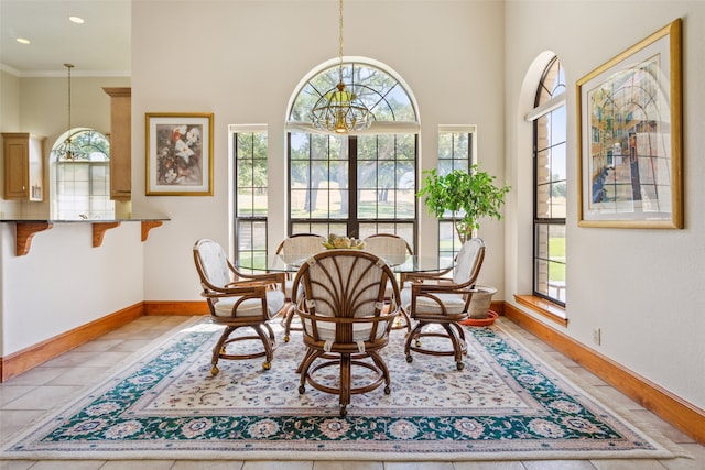 dining area featuring tile patterned flooring, crown molding, and a notable chandelier