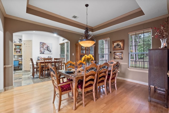 dining area featuring ornamental molding, hardwood / wood-style flooring, and a tray ceiling