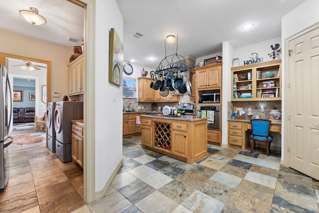 kitchen with built in desk, stainless steel appliances, washing machine and clothes dryer, ceiling fan, and a kitchen island