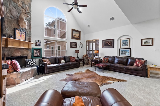 living room featuring light colored carpet, ceiling fan, a stone fireplace, and high vaulted ceiling