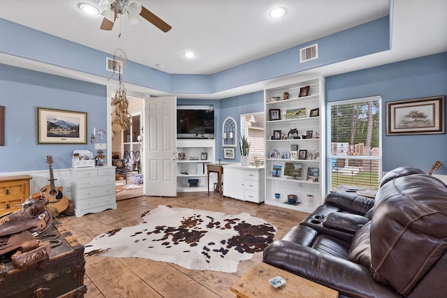 living room featuring built in features, ceiling fan, and light hardwood / wood-style floors