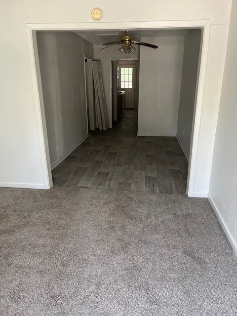 spare room featuring ceiling fan and dark colored carpet