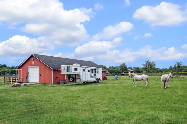 exterior space featuring an outbuilding, a rural view, and a garage