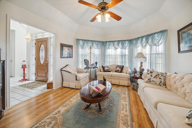 living room featuring light hardwood / wood-style flooring, ceiling fan, and a raised ceiling