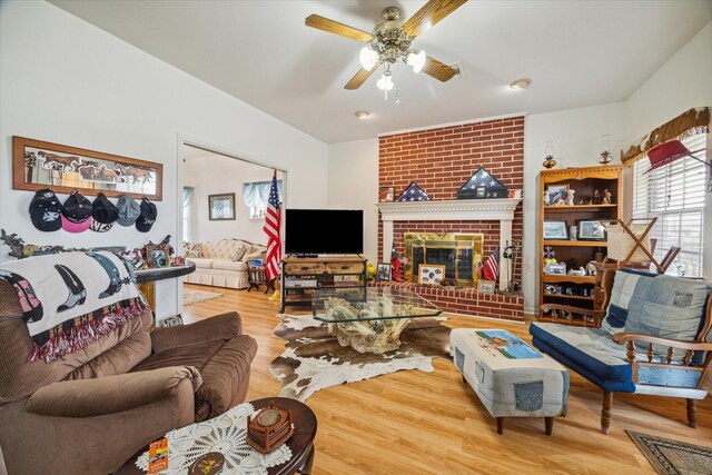 living room with wood-type flooring, a brick fireplace, and ceiling fan