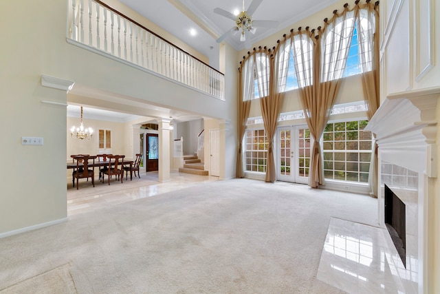 unfurnished living room with a towering ceiling, light carpet, ornamental molding, and ceiling fan with notable chandelier