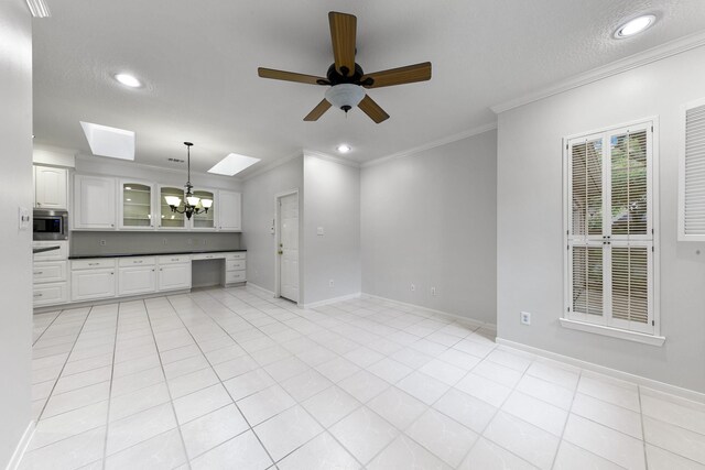 interior space with crown molding, a skylight, built in desk, and ceiling fan with notable chandelier