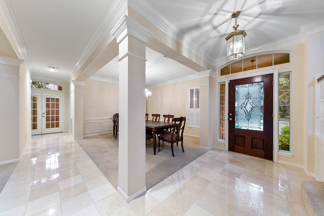 carpeted foyer featuring french doors, ornamental molding, a notable chandelier, and ornate columns