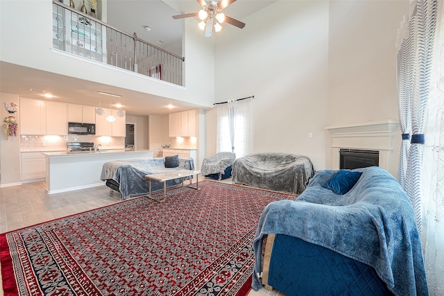 living room with ceiling fan and a towering ceiling