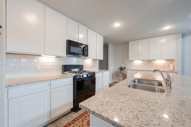 kitchen with black appliances, white cabinetry, and sink