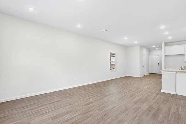 unfurnished living room with sink and light wood-type flooring