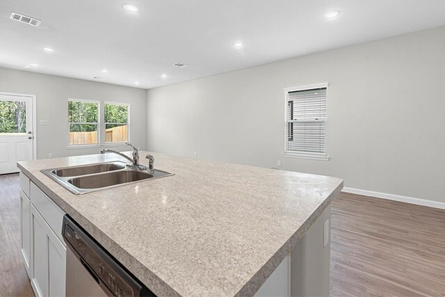 kitchen featuring dishwasher, hardwood / wood-style floors, a kitchen island with sink, sink, and white cabinetry