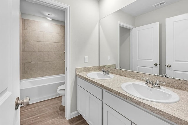 full bathroom featuring vanity, toilet, tiled shower / bath combo, and wood-type flooring