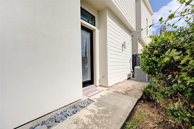 property entrance with cooling unit and stucco siding