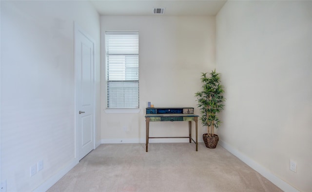 interior space with baseboards, visible vents, and light colored carpet