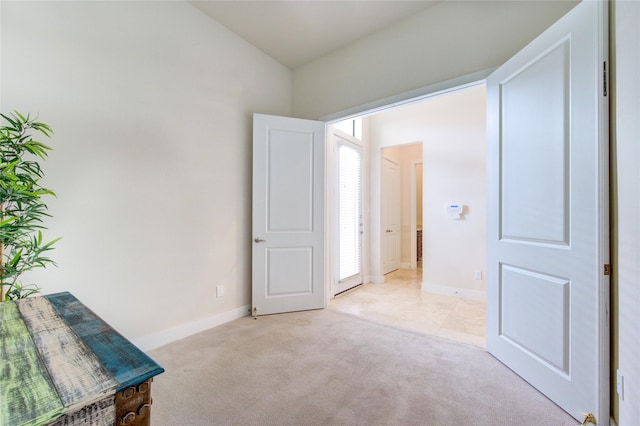 unfurnished bedroom with light carpet, vaulted ceiling, and baseboards