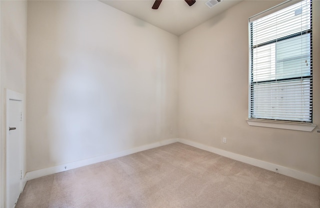 spare room featuring light carpet, visible vents, baseboards, and a ceiling fan