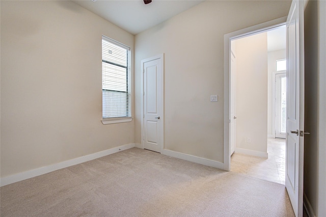 unfurnished room with ceiling fan, baseboards, and light colored carpet