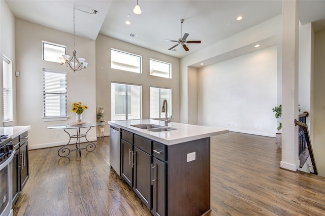 kitchen featuring dark wood-style floors, decorative light fixtures, stainless steel appliances, light countertops, and a sink