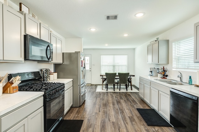 kitchen with plenty of natural light, black appliances, sink, and dark hardwood / wood-style floors