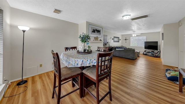 dining space featuring a textured ceiling, hardwood / wood-style flooring, and ceiling fan