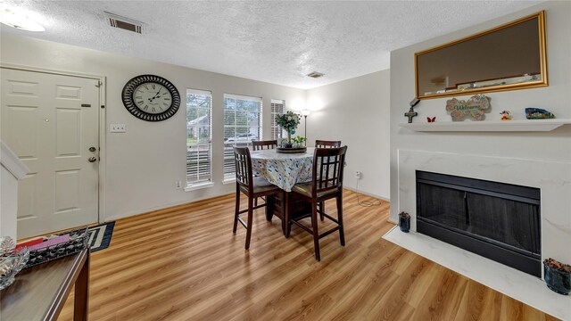 dining room with wood-type flooring, a textured ceiling, and a fireplace