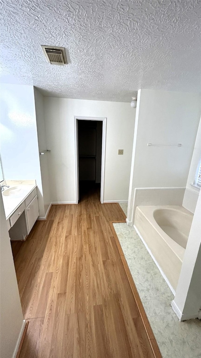 bathroom with a washtub, hardwood / wood-style floors, a textured ceiling, and vanity