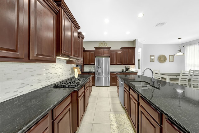 kitchen featuring backsplash, dark stone countertops, light tile patterned floors, stainless steel appliances, and sink