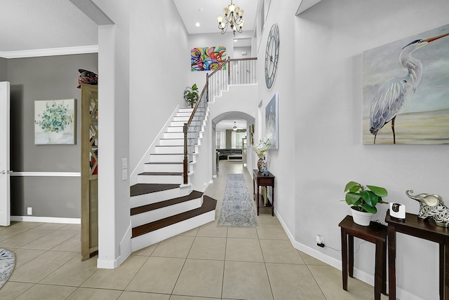 tiled foyer featuring a chandelier and crown molding