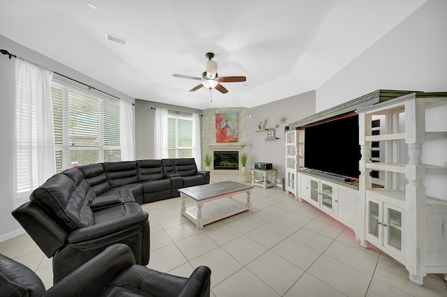 living room with ceiling fan, light tile patterned floors, and a stone fireplace