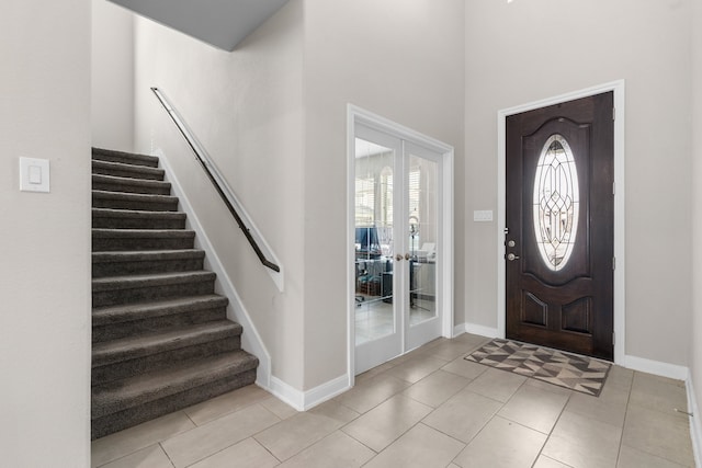 entrance foyer featuring french doors, a healthy amount of sunlight, a high ceiling, and light tile patterned floors