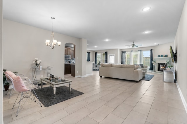 tiled living room featuring ceiling fan with notable chandelier