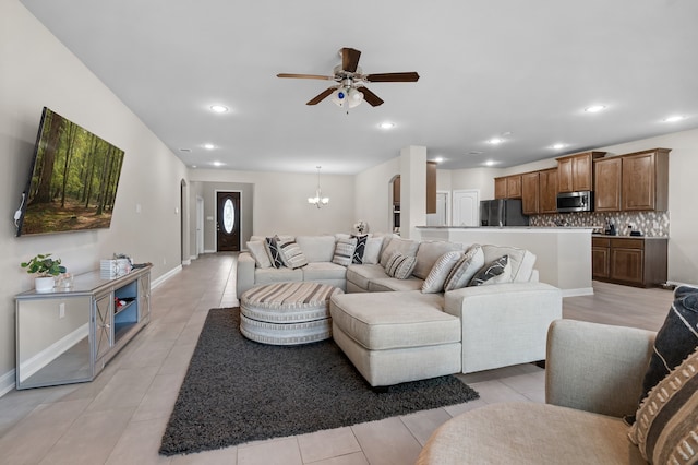 tiled living room with ceiling fan with notable chandelier