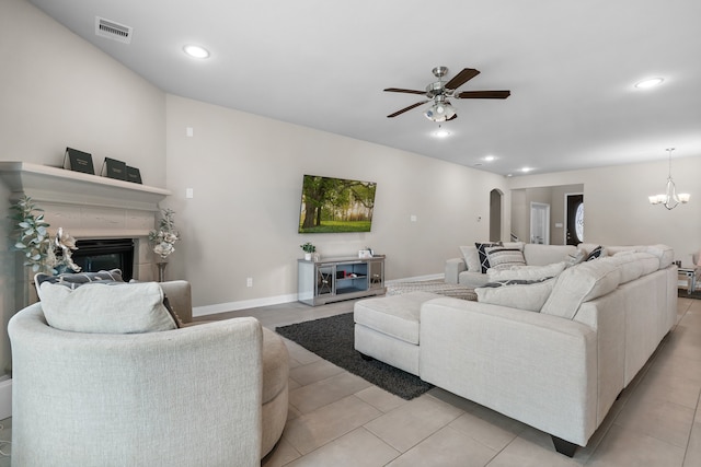 living room with light tile patterned flooring, ceiling fan with notable chandelier, and a tiled fireplace