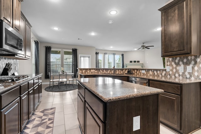 kitchen with stainless steel appliances, a healthy amount of sunlight, a kitchen island, and tasteful backsplash