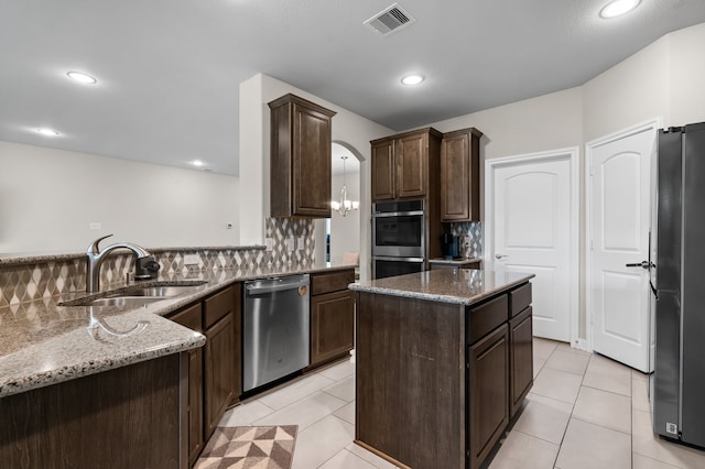 kitchen with backsplash, appliances with stainless steel finishes, stone countertops, pendant lighting, and sink