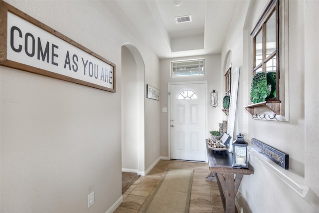 tiled foyer with a tray ceiling