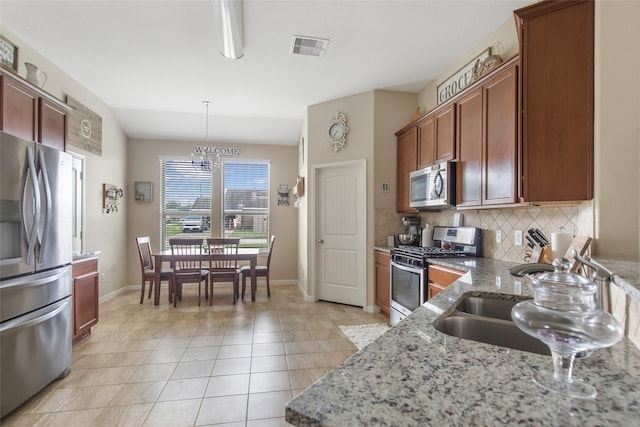 kitchen with light stone countertops, appliances with stainless steel finishes, lofted ceiling, and hanging light fixtures