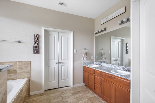 bathroom featuring vanity, a relaxing tiled tub, and tile patterned floors