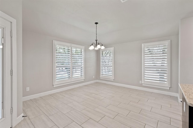 unfurnished dining area with baseboards and an inviting chandelier