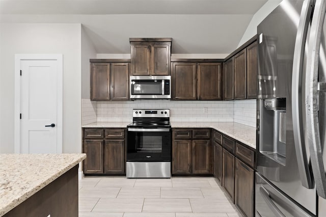 kitchen featuring dark brown cabinetry, light stone counters, stainless steel appliances, and backsplash