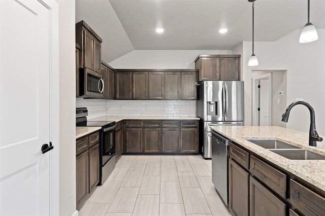 kitchen with hanging light fixtures, vaulted ceiling, appliances with stainless steel finishes, light stone counters, and sink