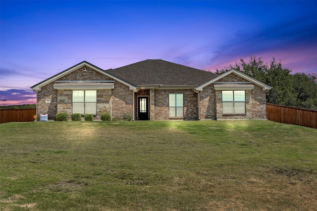 view of front facade with roof with shingles, fence, and a front yard