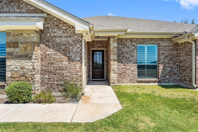 property entrance with brick siding, a lawn, and a shingled roof