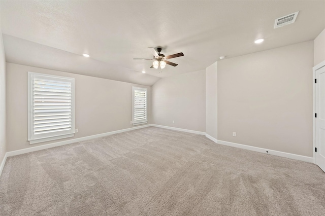 empty room with lofted ceiling, recessed lighting, light carpet, visible vents, and baseboards