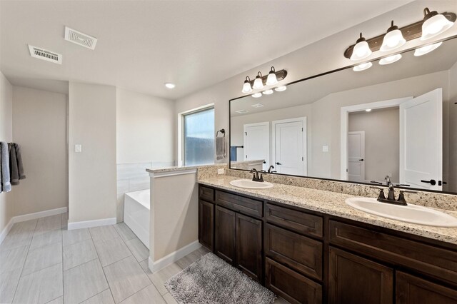 bathroom with tile patterned floors, a relaxing tiled tub, and vanity