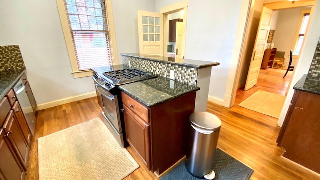 kitchen with light hardwood / wood-style flooring, dark stone counters, and stainless steel gas range