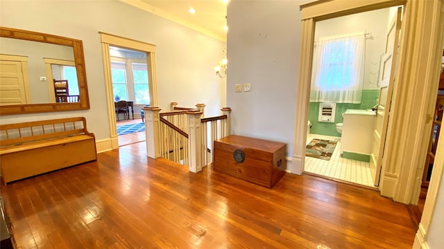 hall featuring hardwood / wood-style floors, ornamental molding, and a notable chandelier