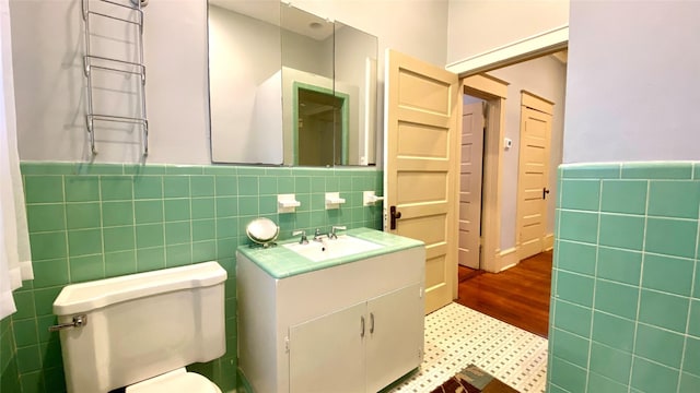 bathroom with vanity, toilet, wood-type flooring, and tile walls